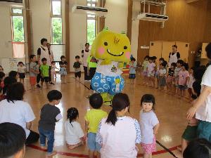 写真：黄色の小鬼のゆるキャラ「えちゴン」の周りを囲むように子どもたちが園になり、みんなでドンガラピッカラ柏崎を踊っているところ