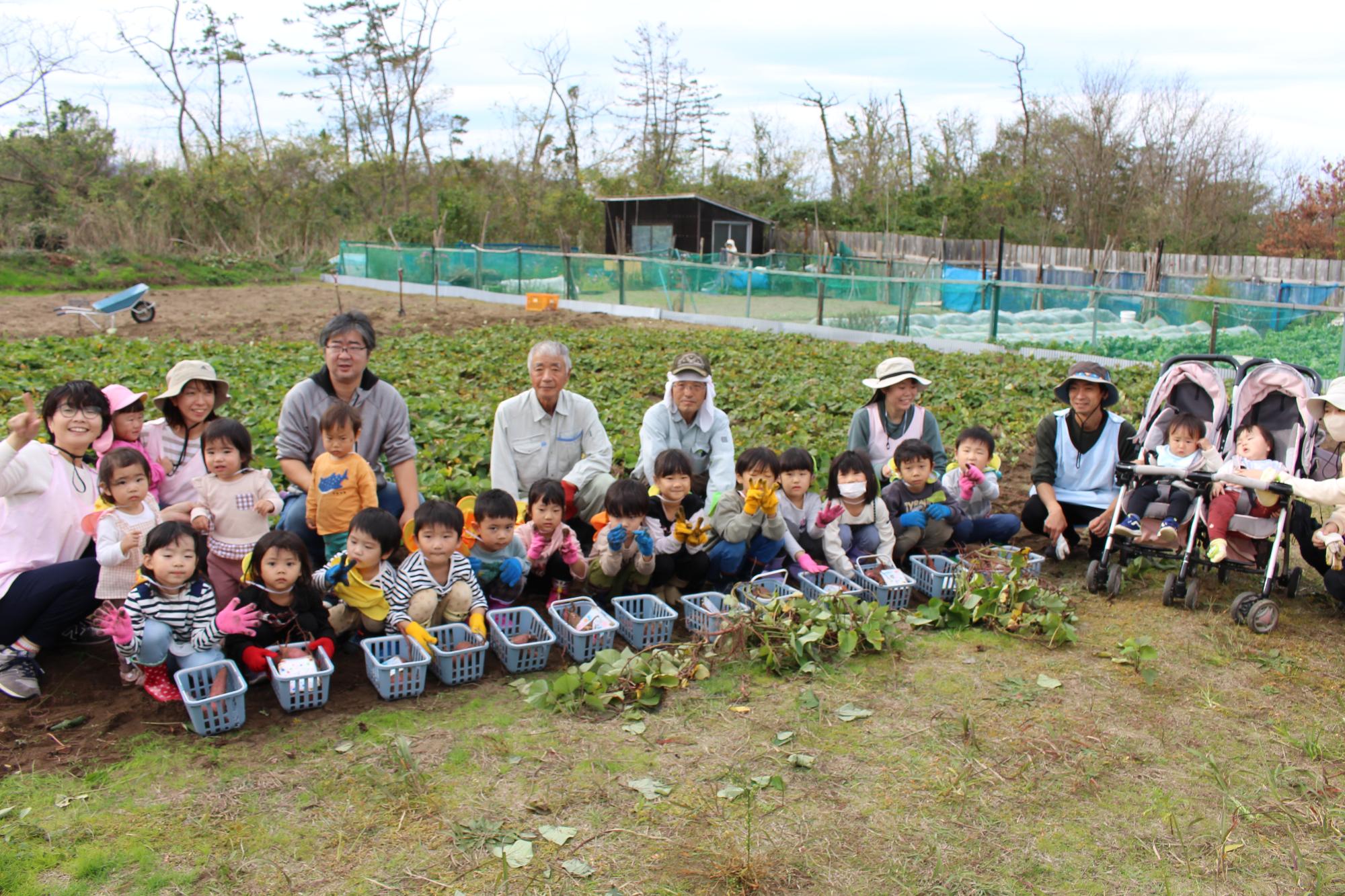 かごに入っている収穫したさつまいもとはまたろうの方との集合写真。