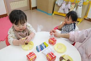 写真：おやつのクッキーを手づかみで食べている2人のひよこ組の園児