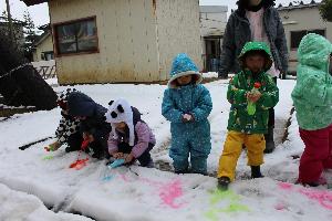 写真：雪に絵の具で色を付けた水をかけて、お絵かきのように楽しむ子どもたち