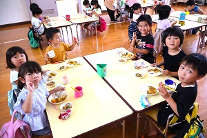 写真：グループごとに机を合わせて、カレーライスをほおばる子どもたち