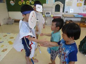 写真：おばけの仮装した年長児と2・3歳児が握手をしている様子