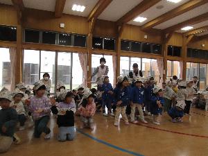 園児が手作り兜をかぶって遊戯室に並び、「こいのぼり」の歌を振り付きでうたっている写真