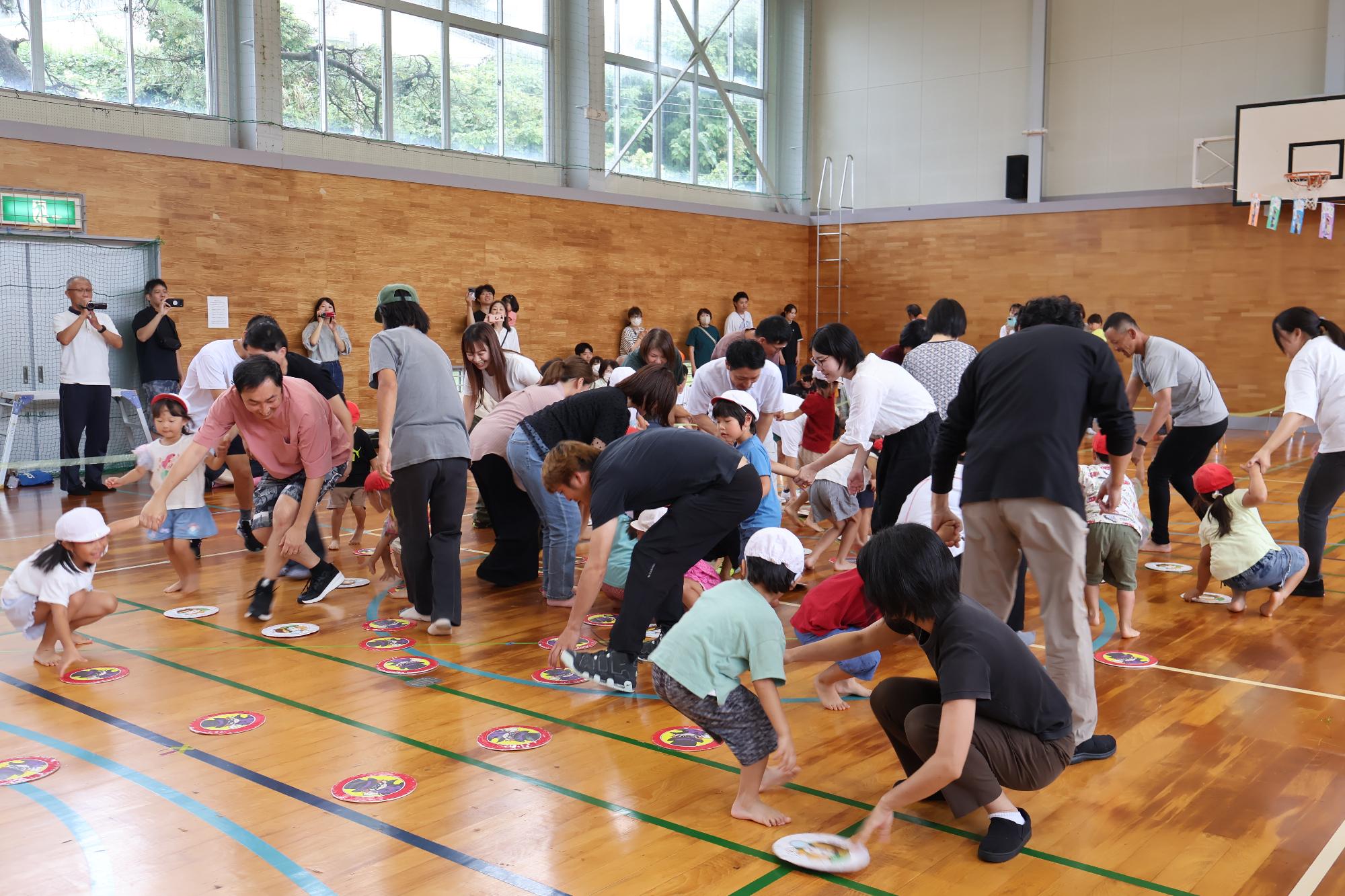 写真：親子で紅組白組に分かれ、自分たちの組の色に紙皿をひっくり返しています。