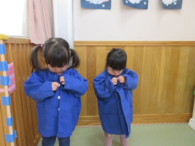 写真：制服のボタンをはめている2人の二歳児