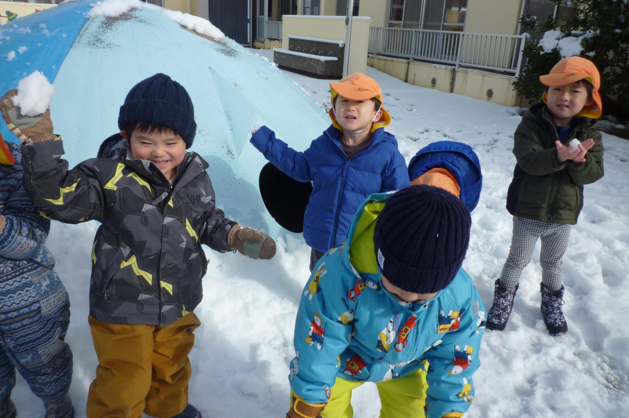写真：3歳児が園庭で雪玉を投げる様子
