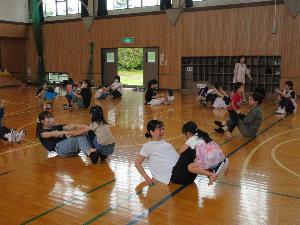 写真：保護者が足を延ばして座り、その足の上に園児がまたがっています。保護者は足を上下させ、子どもたちを持ち上げています。
