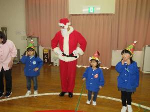 写真：園児とサンタクロースが並んで、両手を腰に当てながら踊っているところ