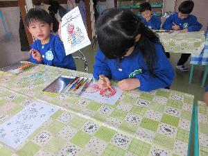 写真：郵便ごっこのはがきに描いてある絵に、園児が色鉛筆で色を塗っているところ