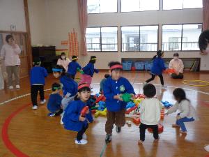 写真：遊戯室中央に置かれたブロックを、1つずつ手にして、チームの陣地に運ぶ子どもたち。