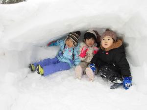 写真：うさぎ組の園児3人が、かまくらの中に座っています