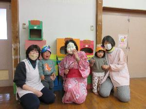 写真：鬼のお面をかぶったひよこ組の子どもたちと並ぶ福の神。福の神に驚いたのか、1人の子は泣き顔です。