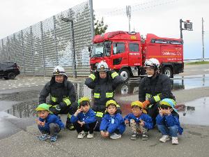 写真：消防車の前で、園児5人と3人の消防士で記念撮影をしてもらいました。