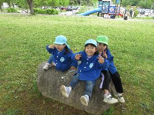 写真：赤坂山公園の大きな石の上で、女児3人がピースサインをしています