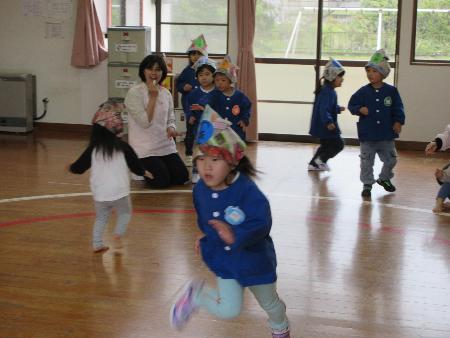 写真：新聞紙の兜を被った子どもたちが遊戯室を走っています