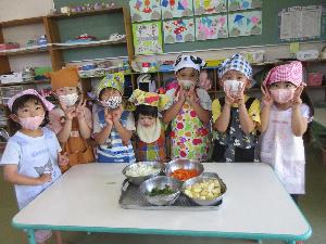 写真：カレー作りに徴したぞう組の子どもたち。切り終えた野菜を前に置いて並んでいます。