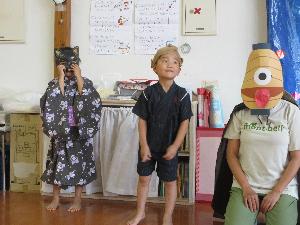 写真：猫のお面をかぶった5歳女児と、のっぺらぼうのお面から顔をのぞかせた5歳男児、提灯お化けに扮した職員が並んでいます
