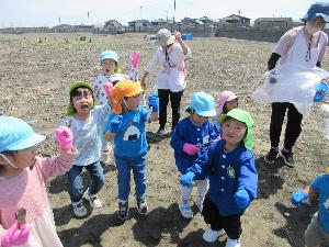 写真：ごみ拾いのスタート前に軍手を付けて手をあげて、気合いを入れる子どもたち