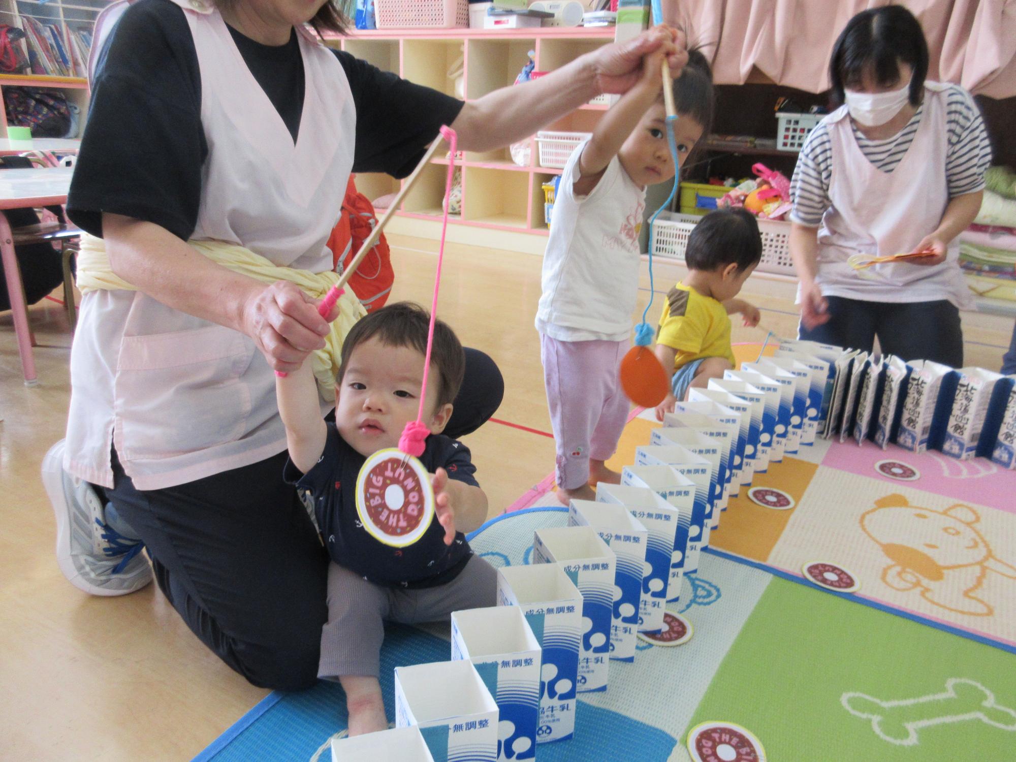 写真：りす組の子どもたちが磁石のついた釣り竿を持って、ドーナツのカードを釣っているところ