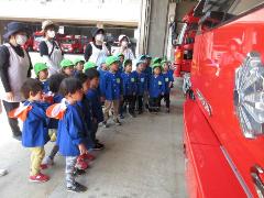 写真：消防車の前で並び、消防士の話を聞いている園児たち