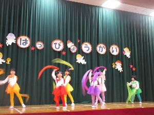 写真：年長女児6人が、カラフルなスカーフを持ち、曲に合わせて揺らしている様子