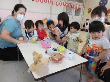 写真：机の上に並んだ動物の風船をじっくりと選ぶ0歳児たち