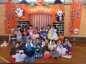 写真：松波コミセンにあるハロウィンの飾り付けの前で、ライオン組の子どもたちが仮装をしている集合しているところ