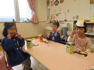 保育室で3人の子どもがおばけちゃんからもらったお菓子を笑顔を見せながら食べている写真