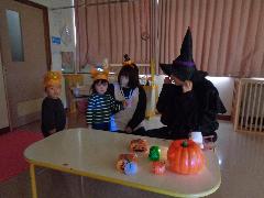 ハロウィンの行事で、ひよこ組の子どもが魔女に仮装した保育者に会いに行っている写真