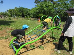 写真：遠足で公園に行って男の子3人がワニの形の遊具に登っているところ
