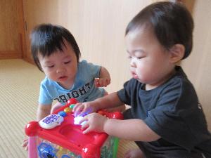 写真：ひよこ組の子ども二人が仲良くおもちゃを操作しているところ