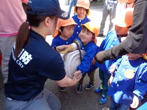 写真：丸くまとめてある消防用の放水ホースを持たせてもらう園児たち