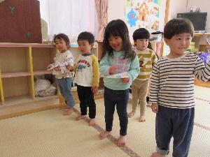 写真：保育室に並び、みんなで一斉に紙飛行機を飛ばしているところ