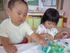 写真：ひよこ組の子ども2人が、色のついた寒天を触ったり型抜きをしたりと、感触遊びを楽しんでいます。
