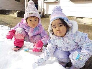 写真：2歳児の子どもたちがヨーグルトの空きカップに雪を詰めて遊んでいます