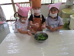 写真：3人のうさぎ組の子どもたちがちぎったピーマンをボウルに入れているところ