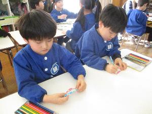 写真：年長児2人が机に向かい、かざまき祭りに招待してもらったお礼を書いているところ