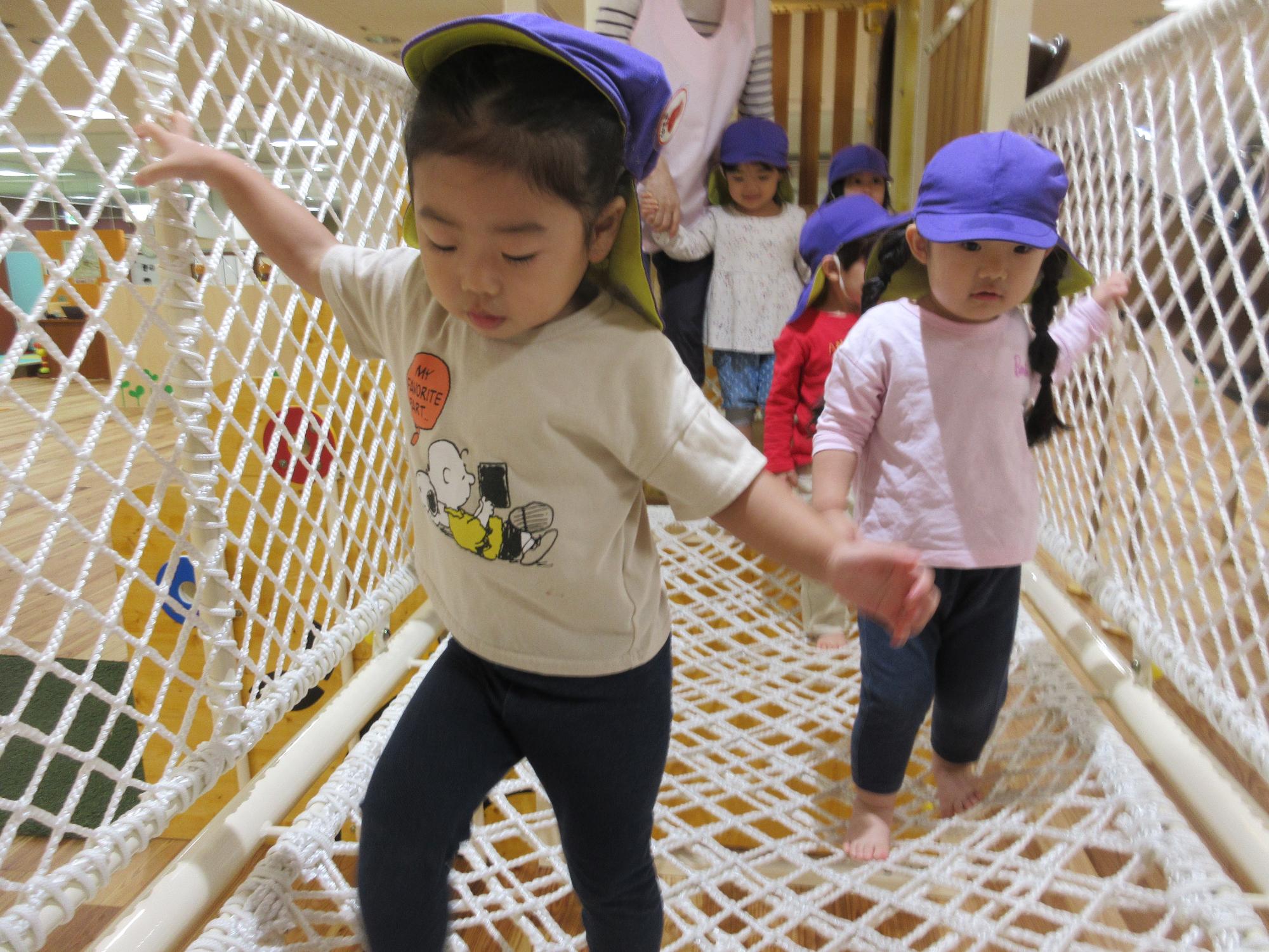 写真：こあら組の子どもたちが、ネット遊具の通路をゆっくりと慎重に進んでいます。