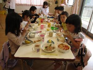 3歳児と4歳児が、保育室内で給食を食べている写真
