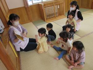 写真：絵本を読み聞かせる保育士の前に、りす組の子どもたちが座っています