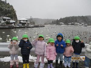 写真：長峰大池の白鳥を背にし、ガードレール沿いに並ぶ3歳児と4歳児7人