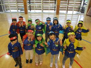 写真：赤緑青黄色のマントとヘアバンド、金のベルトを身につけた4歳児と5歳児13人