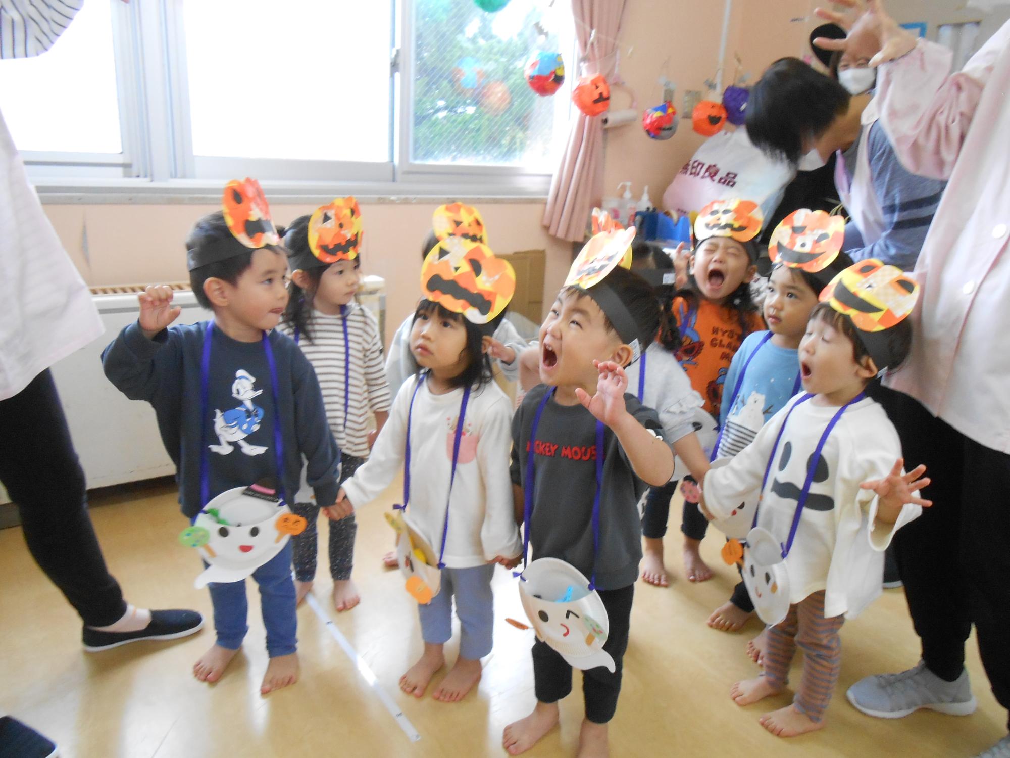 写真：手のひらを顔の横に置き、魔女を怖がらせようと口を大きく開けている子どもたち