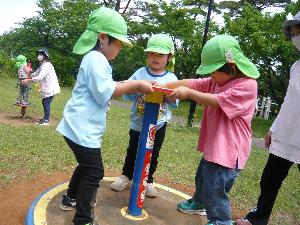 写真：3人の子どもが、回転する遊具で遊んでいる写真