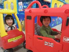 写真：車の遊具をニコニコ顔で運転しているこあら組の子どもたち