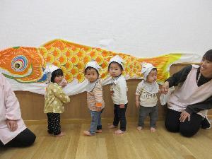 写真：子ども達が壁に貼ってあるこいのぼりに手でタッチをしているところ