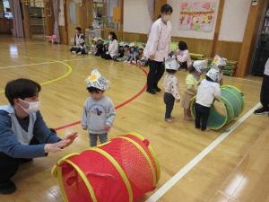 写真：保育者と一緒にりす組の子どもたちがミニトンネルを転がしています