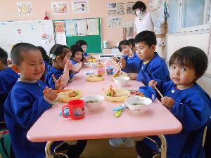 写真：4歳児の子どもたちが椅子に座ってみんなで給食を食べています。