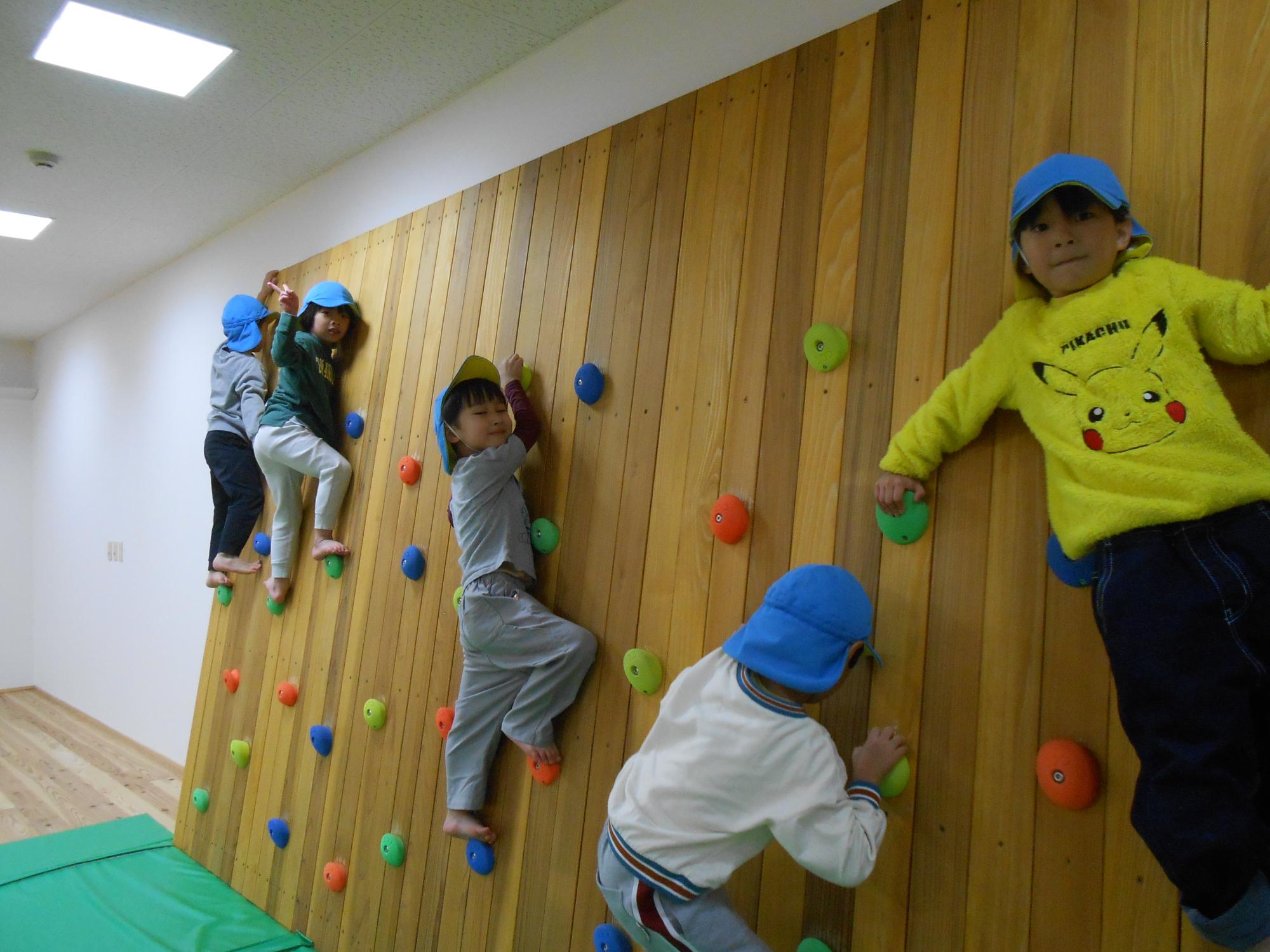 写真：キッズマジックの壁に設置された複数のホルダーに手や足を引っかけ、ボルダリングを楽しむ子どもたち