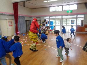 写真：遊戯室に登場した鬼に、新聞紙を丸めた球を投げている子どもたち。鬼退治に一生懸命です。